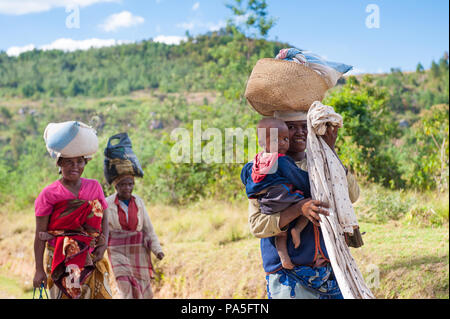 ANTANANARIVO, Madagaskar - 30. JUNI 2011: Unbekannter Madagaskar Frauen ihr Kind tragen und einige andere Dinge, die Straße. Menschen in Madagaskar leiden Stockfoto