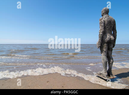 Blick auf das Meer und einen der vielen Gusseisen Figuren, die Antony Gormley von "einem anderen Ort", Crosby Strand, Liverpool Stockfoto