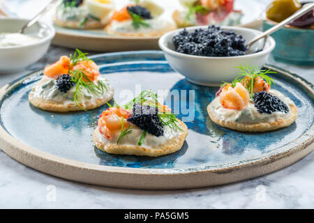 Auswahl an Cocktail Blinis mit Lachs, Langusten, Kaviar und Sauerrahm - gourmet Party Food Stockfoto