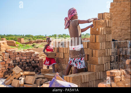 ANTANANARIVO, MADAGASKAR - Juli 3, 2011: Unbekannter Madagaskar Frau macht eine Wand aus Ziegel und ein kleines Mädchen hilft ihr. Menschen in Madagaskar leiden Stockfoto