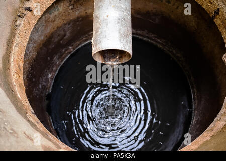 Schmutziges Wasser aus Rohr in die Kanalisation. Ansicht von oben Stockfoto