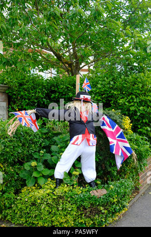 Männliche Vogelscheuche im Garten gekleidet, wie John Bull in dunklen Jacke und eine weiße Hose und halten Union Fahnen und England Flagge Stockfoto