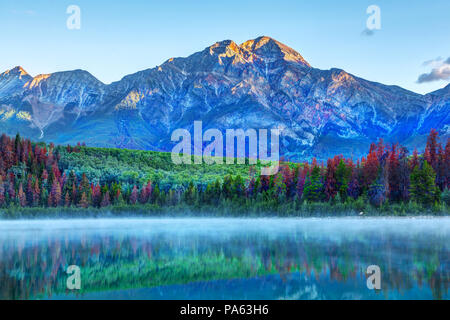 Sonnenaufgang über Patricia Lake im Jasper Nationalpark mit Pyramide Berg im Hintergrund und misty Nebel auf der Oberfläche des Wassers. Ruhiges Wasser erstellen se Stockfoto