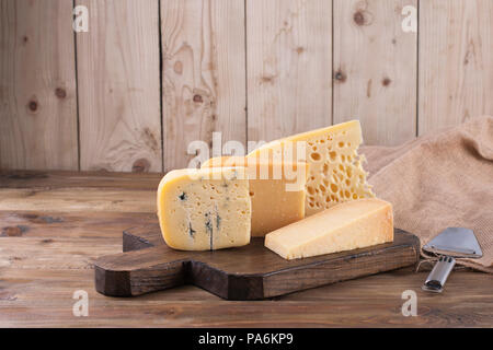 Verschiedene Käse klassische Wahl, auf einer alten Holz- Board, Käsemesser und Stoff Stockfoto