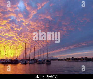 Eine schöne inspirierende rot gefärbten Cirrus cloud Sonnenuntergang Marine über Meer Wasser mit langen Wasser Reflexionen. Foto lage Queensland, Stockfoto