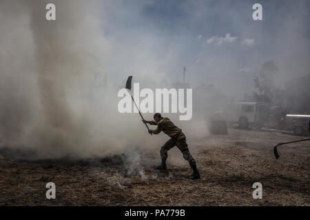 Nahal Oz, im Süden Israels, 21. Juli 2018. Ein israelischer Soldat Hôtels ein Feuer, die angeblich durch einen brennenden Ballon gestartet wurde zu löschen gesendet aus dem Gazastreifen auf einem Milchviehbetrieb in der Nähe des Israeli-Gaza Grenze in Nahal Oz, im Süden Israels, 21. Juli 2018. Die Hamas einen Waffenstillstand mit Israel im Gazastreifen erklärt hat, sagte ein Sprecher der Hamas Anfang Samstag, nach einem Tag der Gewalt, sah ein israelischer Soldat und vier Palästinenser getötet. Foto: Ilia Yefimovich/dpa Quelle: dpa Picture alliance/Alamy leben Nachrichten Stockfoto
