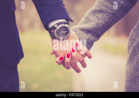 Paar in Liebe Hände halten in Park Outdoor. Ein Mann, der elegante Armbanduhr. Close Up. Stockfoto