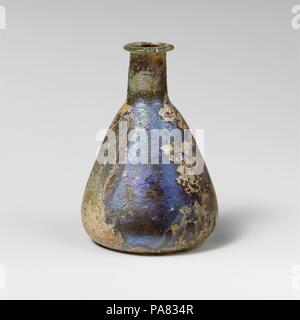 Glas Parfüm Flasche. Kultur: Roman. Abmessungen: Insgesamt: 3 3/16 in. (8.1Cm) Durchm.: 2 3/16 x 13/16 in. (5,6 x 2,1 cm). Datum: 1. Jh. N.CHR.. Farblos mit hellen blau-grüne Färbung. Rim ausgeklappt, über, in, auf der Oberseite abgeflacht; kurz, zylindrische Hals, mit schnittspuren um Base; konischen Körper, an der Basis abgerundet; konkave Unterseite. Komplette, aber beschädigt ist und repariert auf der einen Seite von Rim; viele Pinprick blasen; tiefe Rillen, Mattieren, und irisierenden Verwitterung. Enthält große Schwarz (verbrannt?) die festen Objekt. Museum: Metropolitan Museum of Art, New York, USA. Stockfoto