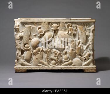 Marmor cinerary urn. Kultur: Roman. Abmessungen: Insgesamt: 14 1/4 x 21 1/4 x 16 1/8 in. (36,2 x 54 x 41 cm). Datum: 1. Halbjahr 1. Jh. N.CHR.. Diese Römische cinerary urn ist sehr ungewöhnlich, dass die Beute des Krieges als das wichtigste Thema. Trotz der fragmentarische Charakter des Stücks, die Trophäen und die Stapel von Waffen und Rüstungen, der Rückseite und den Seiten der geradlinige Cover sind sehr auffällig. Sowohl in der Detail- und Zusammensetzung, die Panels sind repräsentativ für hochwertige Verarbeitung, was darauf hindeutet, dass die Arbeit eine spezielle Kommission war. Leider viel von der Front, wo die Inschrift Aufnahme Stockfoto