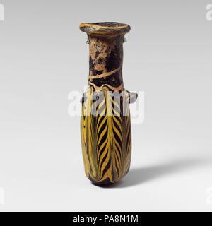 Glas alabastron (Parfüm Flasche). Kultur: Griechisch, östlichen Mittelmeer. Abmessungen: H.: 3 1/8 in. (7,9 cm) Durchm.: 1 1/16 x 1 1/8 in. (2,6 x 2,8 cm). Datum: 3.-2. vorchristlichen Jahrhundert. Transluzente Kobaltblau, mit Griffen in der gleichen Farbe; Trail in opak Gelb. Dicke horizontale Rim-disk, ungleich mit strahlenden Schnittspuren auf Oberfläche geformt; zylindrische Hals, leicht nach unten spitz zulaufend; kleine schräge Schulter; Gerade-seitig zylindrische Körper; konvexen Boden; auf der oberen Körper, zwei Stift griffen, über trail Muster angewendet; eine deutlich größer als die anderen. Trail an der Oberseite des RIM-dis Stockfoto