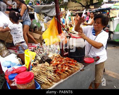 QUEZON CITY, Philippinen - 22. NOVEMBER 2015: eine Frau verkauft, kalte Säfte und eine große Auswahl an Grill auf einem Wagen auf einer Straße in Quezon City, Philippinen Stockfoto