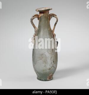 Glas zwei- Flasche. Kultur: Roman. Abmessungen: 4 15/16 in. (12,5 cm) Andere: 1 11/16 in. (4.2 cm) Durchm. Von rim: 1 1/8 in. (2,9 cm) Durchm. Der Fuß: 1 1/8 in. (2,9 cm). Datum: 2.-3.Jh. N.CHR.. Transluzent blau grün; Griffe in der gleichen Farbe. Rim ausgeklappt, rund, und in, mit abgeschrägter äußerer Kante; abfackeln, Lob-seitig Mund; kurz, trichterförmigen Hals, nach unten baut unmerklich mit schlanken bauchigen Körper zu verbinden; integrierter, dick, leicht auch als base Ring; ungleichmäßige, konkav unten; Griff der Stange angewendet in Langen, gecrimpt Pads an Schulter, ausgearbeitet und runden, an Hals und Trail gedrückt Stockfoto