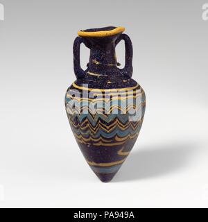 Glas amphoriskos (Parfüm Flasche). Kultur: Griechisch, östlichen Mittelmeer. Abmessungen: H. 3 9/16-in. (9 cm). Datum: Ende 6.-5. vorchristlichen Jahrhundert. Transluzente dunkles Kobaltblau, mit Griffen in der gleichen Farbe; Wanderwege in Opak gelb, opak türkis blau. Breite nach innen geneigte Rim-disk; zylindrische Hals, leicht nach unten erweitern; breit, kantige Schulter; hohe konische Körper, verjüngt sich nach unten hin unten; zwei vertikale Schlaufe Griffe angewendet auf der Schulter nach oben, erarbeitet und auf der Unterseite der RIM-gedrückt-Disk. Eine gelbe Markierung am Rand des RIM-Festplatte angeschlossen; eine andere gelbe Weg zu n Stockfoto