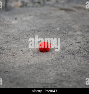 Rote wollene Ball liegt auf dem grauen Asphalt, Tag Stockfoto