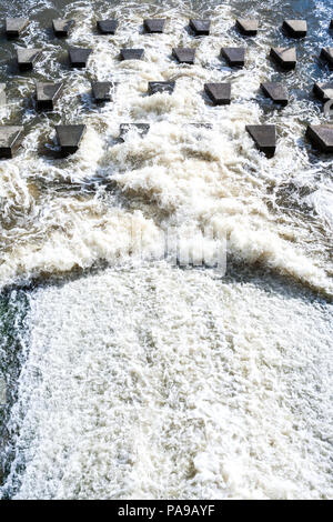 Top perspektivische Ansicht der schäumende Wasser Absturz auf kleinen Beton Steine - wellenbrechern. Stockfoto