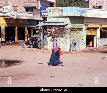 Indische Frau entlang einem Dorf Straße Brennholz tragen auf dem Kopf, Jaipura, Rajasthan, Indien. Stockfoto