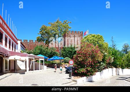 Blick auf die mittelalterliche Burg mit Touristen zu Fuß entlang einer Straße der Stadt im Vordergrund, Silves, Portugal, Europa. Stockfoto