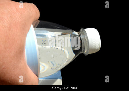 Eine Flasche Wasser kann als Lupe verwendet werden, hier hilft es, lesen das Mindesthaltbarkeitsdatum auf Milch Stockfoto