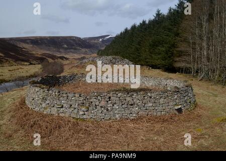 Ein runder Stein Schafstall Mit einer zerstörten Broch hinter, in Glen Loth, Scottish Highlands. Der Stein für den Schafstall wurde wahrscheinlich von der Broch genommen. Stockfoto