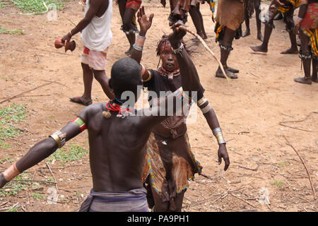 Hamer Mann spannend eine Frau während der Stier springen Zeremonie (Ukuli ritual) von Hamer Hamar Stamm, Äthiopien Stockfoto