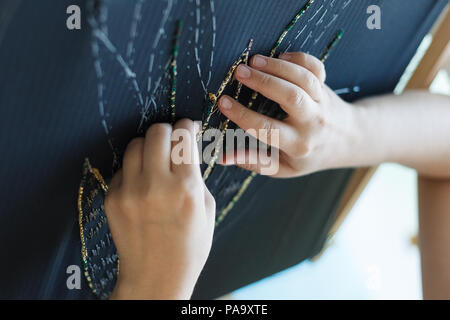 Stickerei mit Frau Hände der Blüte mit Perlen. Schwarzem Stoff und die Hände. Atelier oder Design Studio zur Anpassung. Nähe zu sehen. Stockfoto