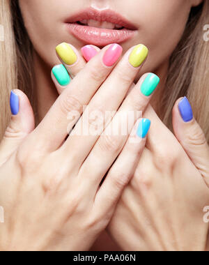 Junge blonde Frau mit Spaß verschiedenfarbige Fingernägel Maniküre. Stockfoto