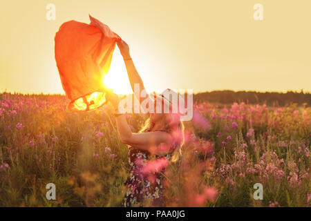 Mädchen in einem Feld von Blumen genießt die Natur auf den Sonnenuntergang. Stockfoto