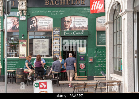 Leute hinsetzen und ein Bier vor einem Pub in Irland genießen. Ein Mann in der Tür stehen. Stockfoto