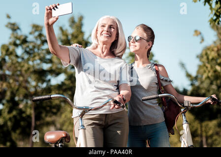 Moderne Oma ihre rechte Hand heben mit Telefon Stockfoto