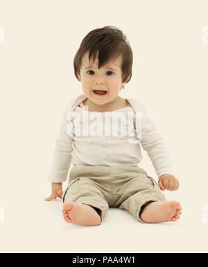 Lustige Baby sitzen auf dem Boden isoliert auf weiß Stockfoto