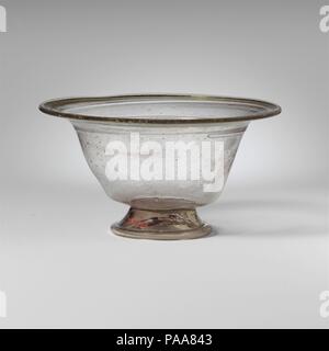 Glasschale. Kultur: Roman. Abmessungen: 3. 7,6 cm (3 Zoll) Andere: 5 3/16 in. (13,2 cm) Durchm. Der Fuß: 2 3/8 in. (6,1 cm). Datum: 4.Jahrhundert N.CHR.. Farblos mit hellgrünen Farbton und hell-lila Streifen; Basis und Trail in den gleichen Farben. Horizontale abgerundet und verdickte Felge mit leicht nach unten Knicken auf der einen Seite; breit, abfackeln Mund, trichterförmigen Seiten zu Körper, gedreht in stark unter; angewandte Abfackeln mit dicken Tubular Base Ring; Ungleichmäßige, aber flachen Boden mit off-center pontil Narbe. Schüssel steht aslant auf Basis Ring. Feine trail auf der Unterseite der Mund angewandt, Wunde 2 1/2 mal um die Oberseite des Körpers, ein Stockfoto