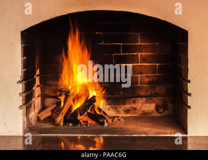 Feuer in einem Kamin mit Überlegungen über einen Stein. Abendlicht Stockfoto