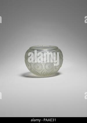 Cut-Glass Cup. Abmessungen: H.2 3/4 in. (7 cm) Durchm. 3 5/8 in. (9,2 cm). Datum: 8. bis 9. Jahrhundert. Festplatten mit erhöhten Punkten am Zentrum umschließen den Körper dieses kleine kugelförmige Schale. In Anlehnung an die Omphalos (NABEL-förmigen) Motiv auf Objekten aus der neunten Jahrhundert Samarra gefunden, Entwürfe wie die hier zu sehen sind von Sassanidischen geschliffenes Glas inspiriert. Der Hersteller erreicht eine harmonische Oberflächenbehandlung durch das Abtrennen der umliegenden Glas, aus dem Kreise in der Entlastung. Blütenblätter strahlenförmig von der kreisförmigen Unterseite im unteren Teil der Schale dekorieren. Museum: Metropolitan Museum of Art, New York, USA. Stockfoto