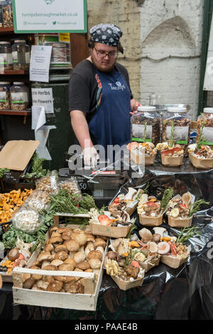 Ein Unternehmer, der eine frische Vielfalt der Pilze auf einem am Borough Market in London. Stockfoto