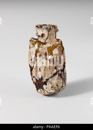 Glas Flasche wie ein Datum geprägt. Kultur: Roman. Abmessungen: H.: 2 3/16 in. (5.6 cm) Durchm.: 3/4 x 1 1/4 in. (1,9 x 3,2 cm). Datum: Mitte-1st bis zum frühen 2. nachchristlichen Jahrhundert. Transluzente gelblich-braun. Dick, uneben, Rim, leicht auch als und gefalteten Runden und in; zylindrische Hals, drückte sich in Körper, die hohle Schulter; ungleichmäßige, zylindrische Körper; abgerundet aber einseitig unten. Eine kontinuierliche Form der Naht um Körper, Verlängerung des Halses nach oben. Körper in der Form eines gefalten Datum, aber mit Muster von mehr regelmäßigen vertikalen Kanten und Vertiefungen. Gebrochen und repariert, mit sechs verbleibenden Bohrungen Stockfoto