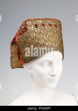 Hut. Kultur: Russisch. Datum: 4. Quartal 18. Kopfbedeckungen oder kokoshniks hatte die größte Fülle von Verzierungen von jeder Art von Kleidungsstück in Russland. Sie waren meist aus Damast mit vergoldeten metallischen Fäden oder Samt mit Goldstickerei gewoben. Die wohlhabenden Bauernstandes häufig ihre kokoshniks mit Perlen und Edelsteinen verziert. Ihre dekorative Elemente wurden Vertreter der Regionen, in denen sie gebildet wurden. Die aus dem Norden wurden mit dem Fluss Perlen, die in diesem Gebiet reichlich vorhanden waren, während Gänsedaunen und Kammgarn Stickereien waren mehr beliebt in der Sab verschönert Stockfoto