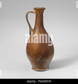 Glaskanne. Kultur: Roman. Abmessungen: 4 5/8 in. (11,8 cm) Andere: 2 3/16 in. (5,5 cm) Durchm. Von rim: 7/8 in. (2.3 cm) Durchm. Der Fuß: 1 3/8 in. (3,5 cm). Datum: 1. Jh. N.CHR.. Farblos mit bläulichen Farbton; in gleicher Farbe. Ungleichmäßige rim ausgeklappt, über, und in; konkave Nacken, joinging unmerklich mit Schulter; ovoide Körper; integrierter Base Ring mit ausgeprägter nach außen falten; flache Unterseite; Griff der Stange in einem großen Block, auf der Schulter, erarbeitet und nach außen, nach innen gewölbt, und drückte auf der Hals nach oben, mit Trail endet am äußeren Rand der Felge. Intakt, außer für kleine Bohrung in der Schulter; pinpr Stockfoto