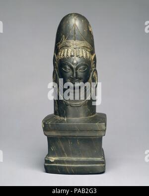 Linga mit Gesicht von Shiva (Ekamukhalinga). Kultur: Indien (Jammu und Kashmir, alte Königreich von Kaschmir). Abmessungen: H 14. (35,5 cm). Datum: 7. Shiva manifestieren sich in der menschlichen Form, die sich aus der linga Welle ist ein gefeierter Darstellung des Gottes, die zum Vorsprung in Nordindien während des fünften Jahrhunderts stieg. In dieser meisterhaften Rendering, der stattliche Gesicht gibt ein süßes Gesicht zu dieser komplexen Gottheit; er zeigt das dritte Auge der höchsten Weisheit, trägt große Ohrstöpsel, und hat seine gewelltes Haar bis zu einem double-loop Chignon durch ein Halbmond eingerichtet, seine Unterschrift Motiv. Stockfoto