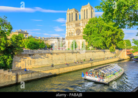 Paris, Frankreich, 1. Juli 2017: Bateaux-Mouches mit vielen touristischen während einer Reise bei Sonnenuntergang auf dem Fluss Seine mit der Kathedrale von Notre Dame auf der Ile de la Cite auf Hintergrund. Sonnigen Tag, blauer Himmel. Stockfoto