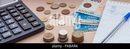 Notizblock mit Kugelschreiber, Rechnungen, verschiedenen Geld und einen Rechner auf dem Tisch. Stockfoto