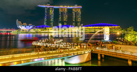 Singapur - 27. April 2018: Symbol von Singapur Merlion Statue, drei Türme von Marina Bay Sands, ArtScience Museum und Esplanade Bridge. Nachtleben in der Marina Bay Harbor in der Nacht. Stockfoto