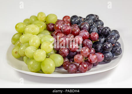 Schwarz, Rot, Grün kernlose Trauben in einer tiefen weiße Schüssel auf einem weißen Geschichte warten auf Frühstück gegessen zu werden. Stockfoto