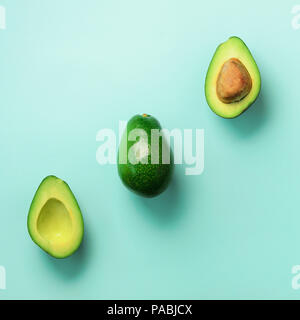 Organische Avocado mit Saatgut, Avocado Hälften und ganze Früchte auf blauem Hintergrund. Ansicht von oben. Pop Art Design, kreative Sommer essen Konzept. Grüne Avocados Stockfoto