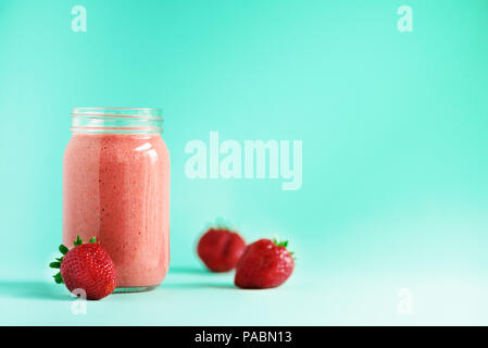 Leckeres Obst und Beeren smoothie Milchshake in einer netten Flasche auf einem blauen Hintergrund mit Beeren um für Happy morgen Stockfoto
