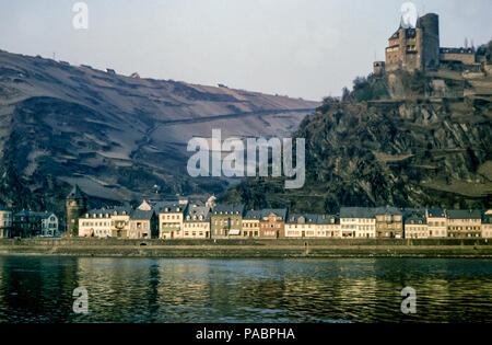 Blick über den Rhein auf den Gipfel des Katz-Schlosses mit seinen sonnendurchfluteten historischen Gebäuden, die sich im Wasser spiegeln, St. Goarshausen, Rheintal, Deutschland in den 1960er Jahren Stockfoto