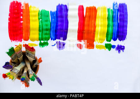 Kunst und Kreativität Konzept mit Streifen von Helle, lebendige Lackierung in den Farben des Regenbogens und ein Glas voll mit schmutzigem bunten Pinsel bilden eine fr Stockfoto