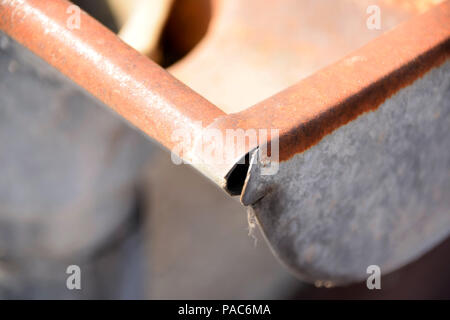 Nahaufnahme Blick auf einen Teil der alten und rostige Dachrinnen mit verbogenen Metall, rostige Dachrinnen Stockfoto