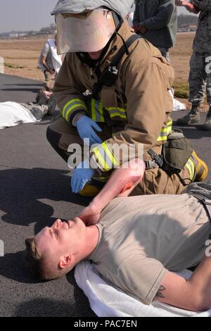 Airman 1st Class Joshua Scott, 51. Bauingenieur Squadron Feuerwehrmann, untersucht einen simulierten Verletzten Opfer während der Übung Beverly 24.00 Uhr 16-01, 9. März 2016, am Osan Flughafen, Republik Korea. Dieses Szenario eine C-130H Hercules Cargo Aircraft zum 374. Airlift Wing von Yokota Air Base, Japan, die simulierten Waffen Feuer von gegensätzlichen Kräfte bei der Landung nahm zugeordnet. Notfallhelfer aus der Feuerwehr, Sicherheitskräften und medizinische Gruppe schwärmten die Szene Hilfe für die simulierten Kausalitäten zu stellen. (U.S. Air Force Foto: Staff Sgt. Benjamin Sutton/Rele Stockfoto
