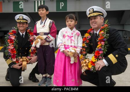 160313-N-IK 337-012 BUSAN, Südkorea (13. März 2016) - Hintere Adm. Ron Boxall, Commander, John C Stennis Strike Group, (rechts) und Kapitän Gregor Huffman, USS John C Stennis" (CVN 74) kommandierenden Offizier, (links) pose mit zwei Südkoreanische Kinder für ein Foto während der Begrüßungszeremonie. Die Bereitstellung einer bereit, Kraft für die Sicherheit und Stabilität in der Indo-Asia - Pazifik, Stennis arbeitet als Teil der Großen Grüne Flotte in regelmäßigen 7 Flotte Bereitstellung. (U.S. Marine Foto von Mass Communication Specialist 3. Klasse Christopher Frost-/Freigegeben) Stockfoto
