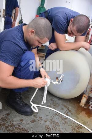 Petty Officer 2nd class Engel Carballo, einen bootsmann mate, bietet Linie Spleißen Ausbildung Seaman Apprentice Nicholas Tribelli, sowohl an Bord USCGC Kukui (WLB 203) stationiert, während im westlichen Pazifischen Ozean, 12. März 2016 im Gange. Carballo und Tribelli ersetzt Linien für Kotflügel des Schiffes als Teil der täglichen Aufgaben. (U.S. Coast Guard Foto von Petty Officer 2. Klasse Melissa E. McKenzie/Freigegeben) Stockfoto